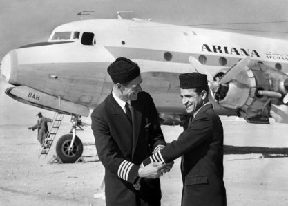 Captain Everett W. Wood, Ariana Chief Pilot and Pan Am instructor, presents pilot stripes to Enaam-ul-Haq Gran. Captain Gran was the first Afghan pilot of Ariana Airlines to receive command status for a four-engine aircraft.